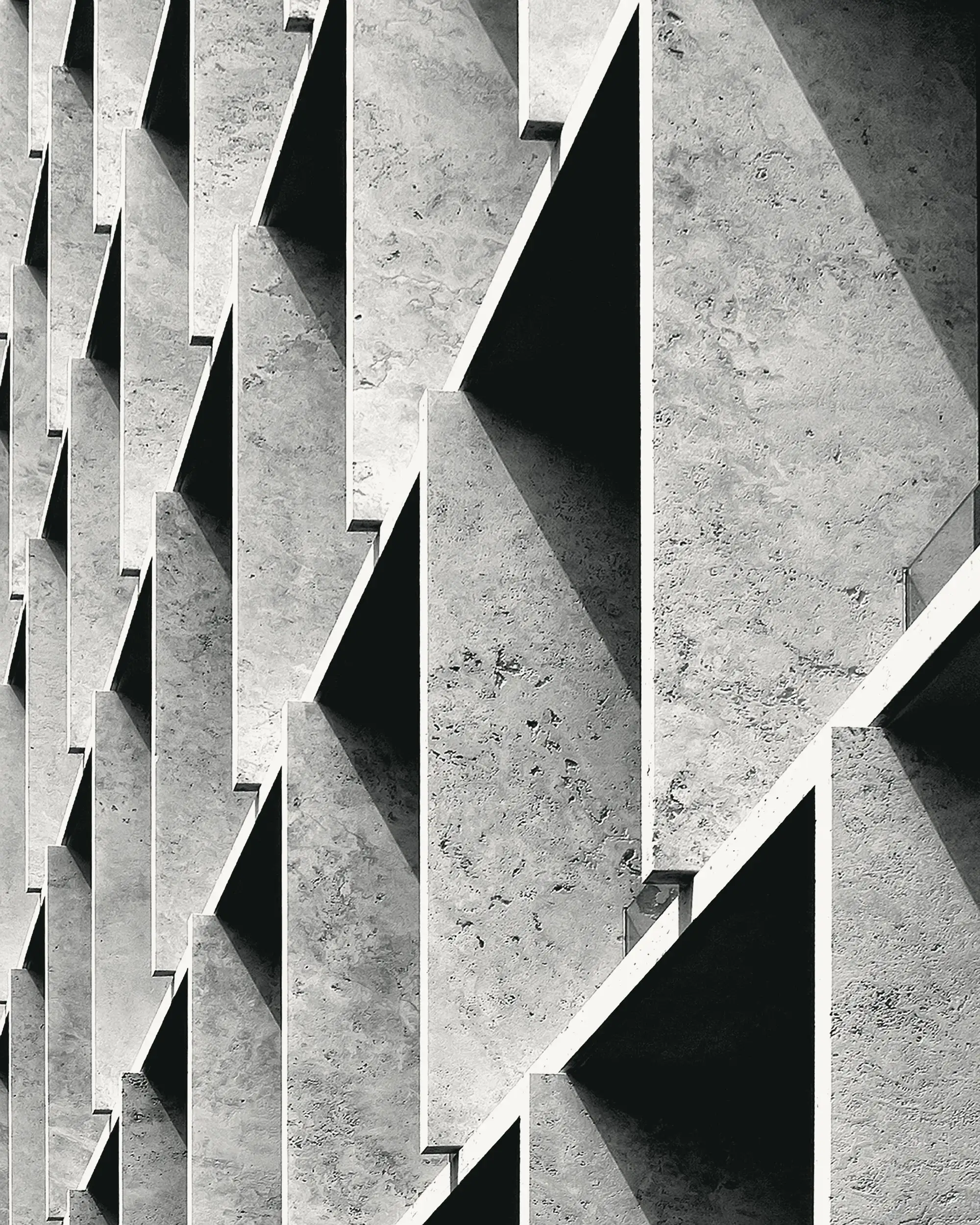 Aletas de concreto en diagonal con sombras duras, blanco y negro, repetición fuerte.